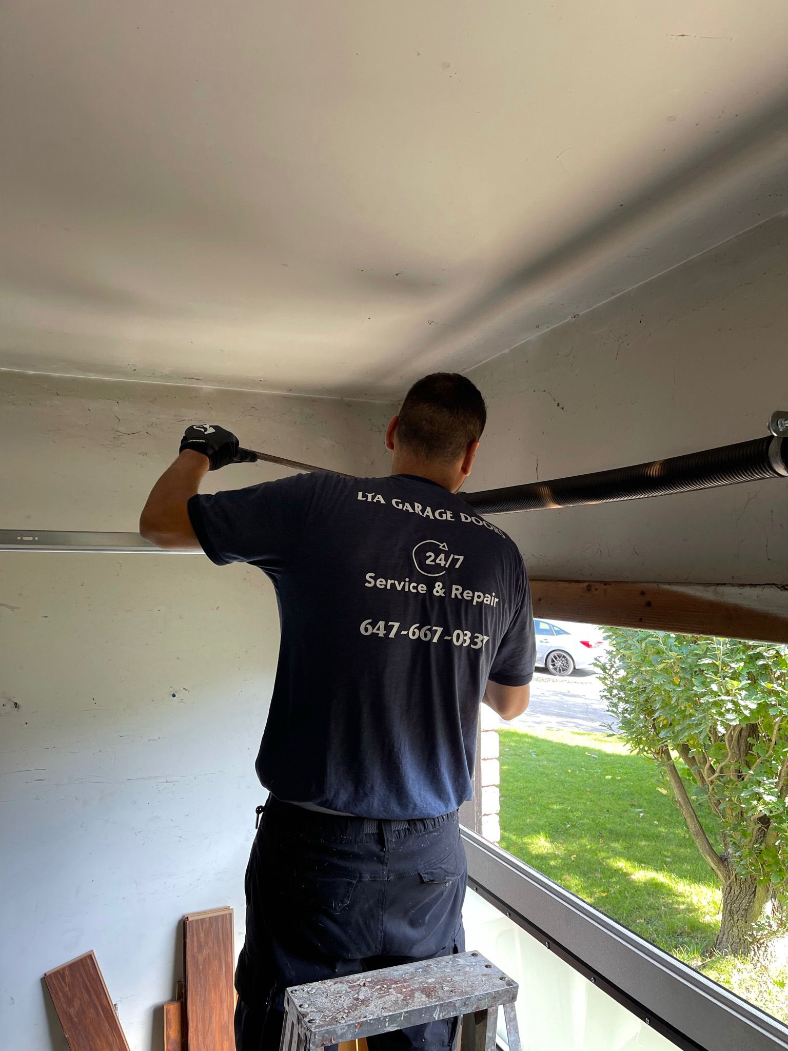 LTA Garage Doors technician replacing a torsion spring from inside a residential garage